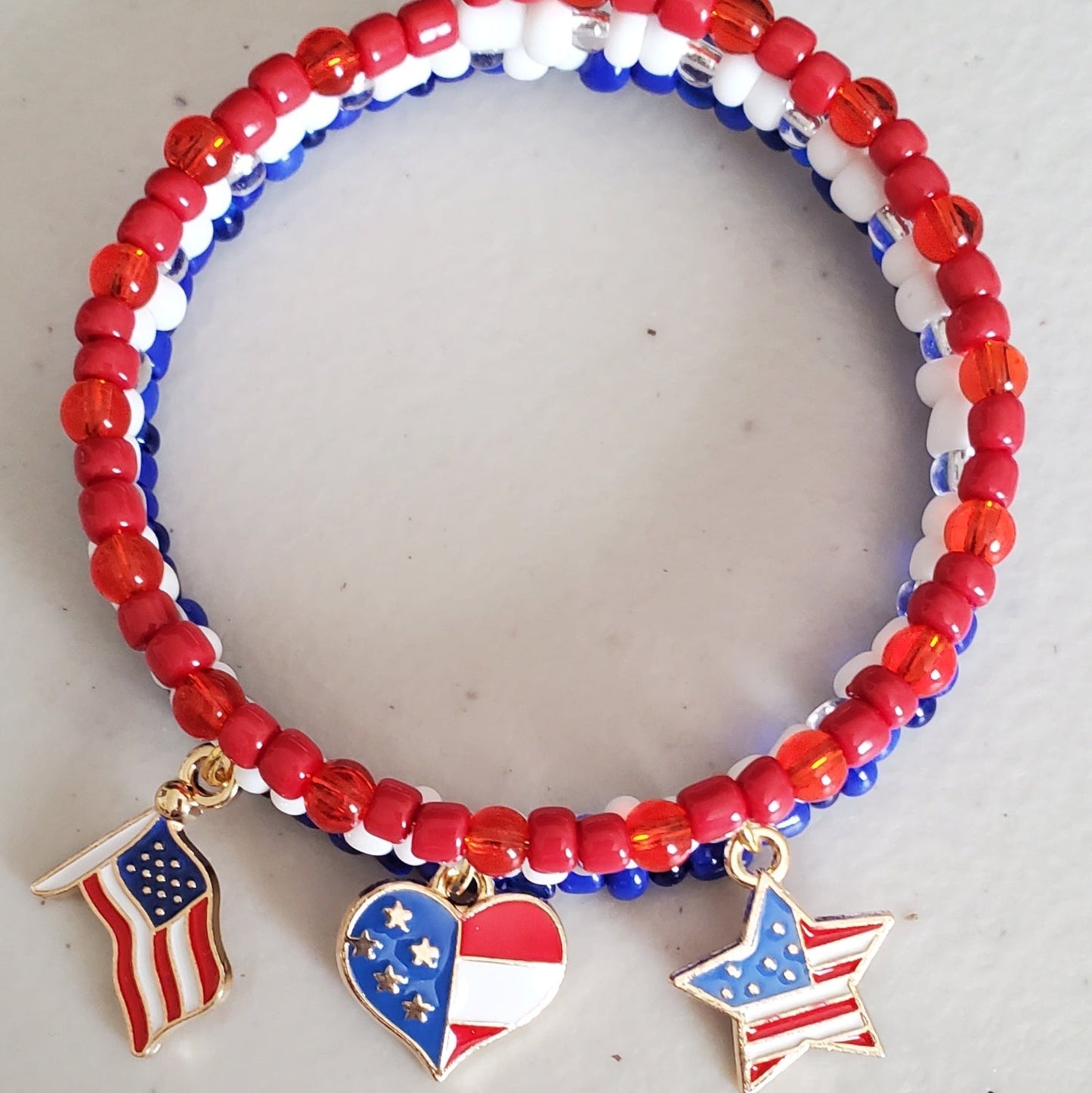 Patriotic charm bracelet with red, white, and blue Czech glass beads and brass flag, heart, and star charms.