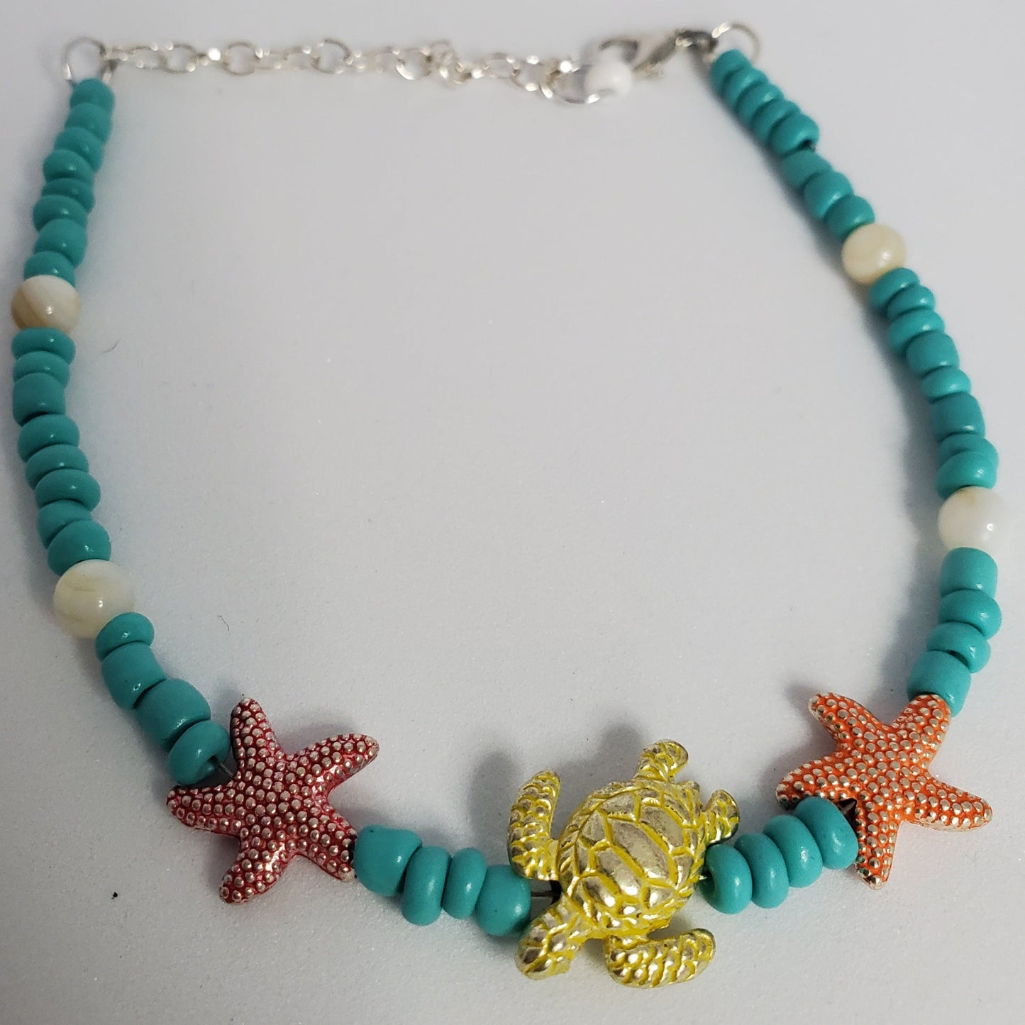 Anklet with turquoise beads, starfish, and turtle charm on a white background