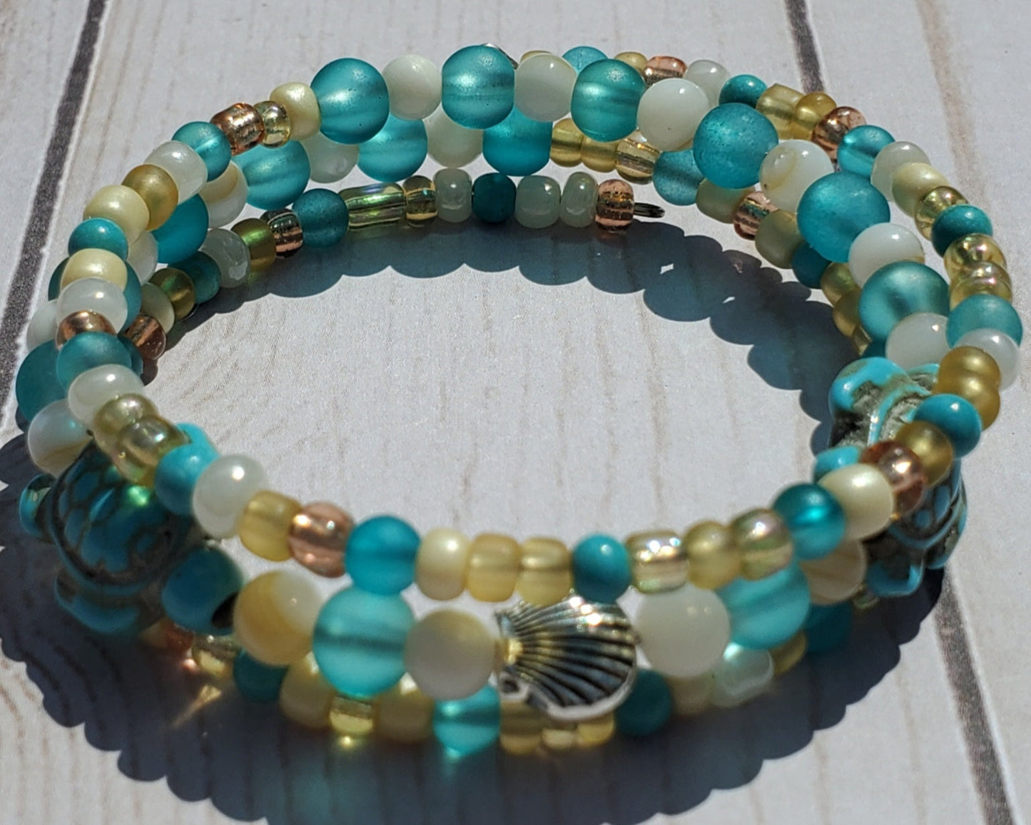 Multicolored beaded bracelet with a shell charm on a wooden surface