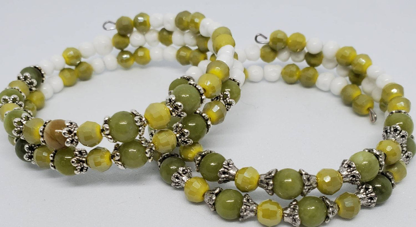 Handcrafted gemstone bracelet featuring green peridot and yellow Japanese glass beads with silver-plated accents on a memory wire cuff.
