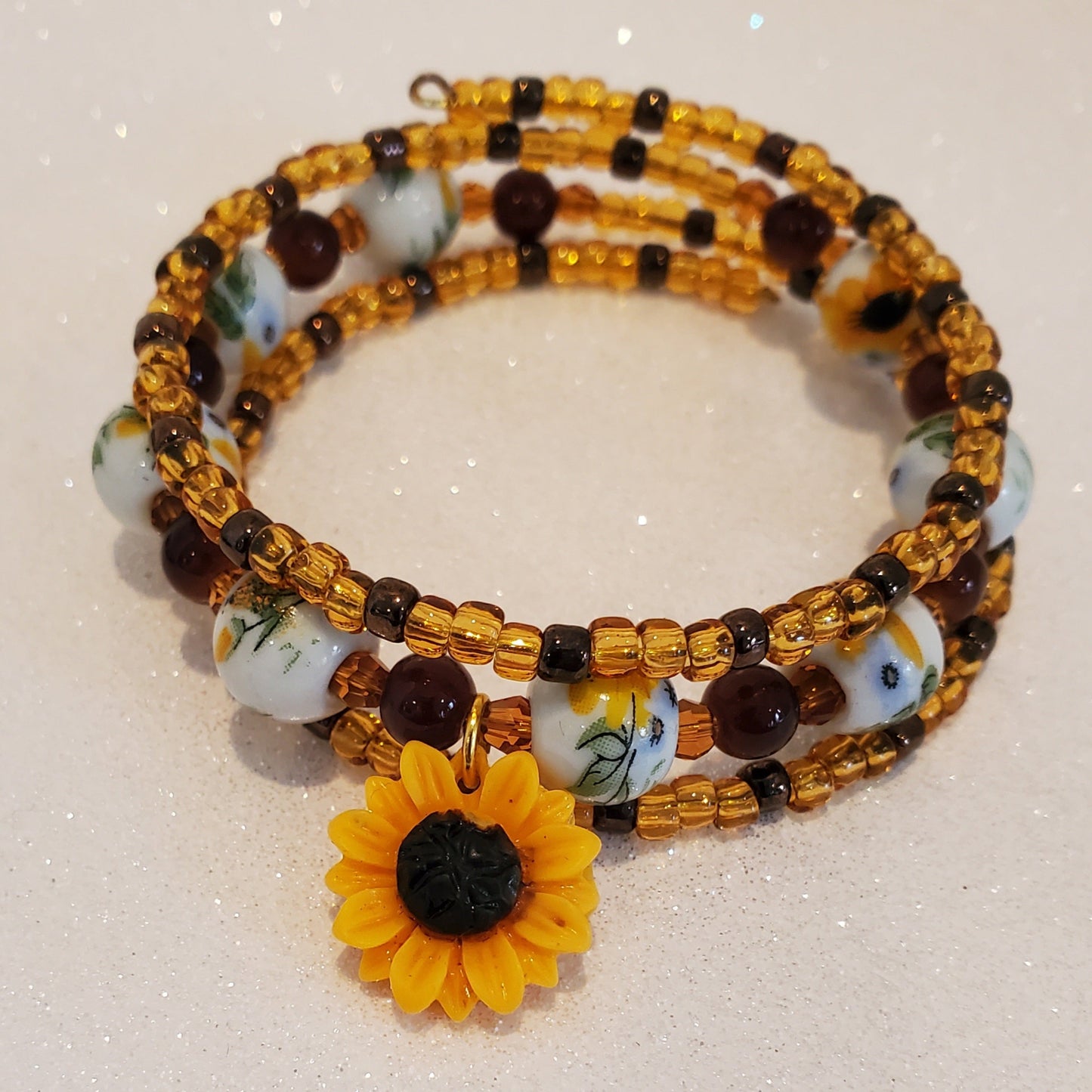 Beaded bracelet with a sunflower charm on a light background