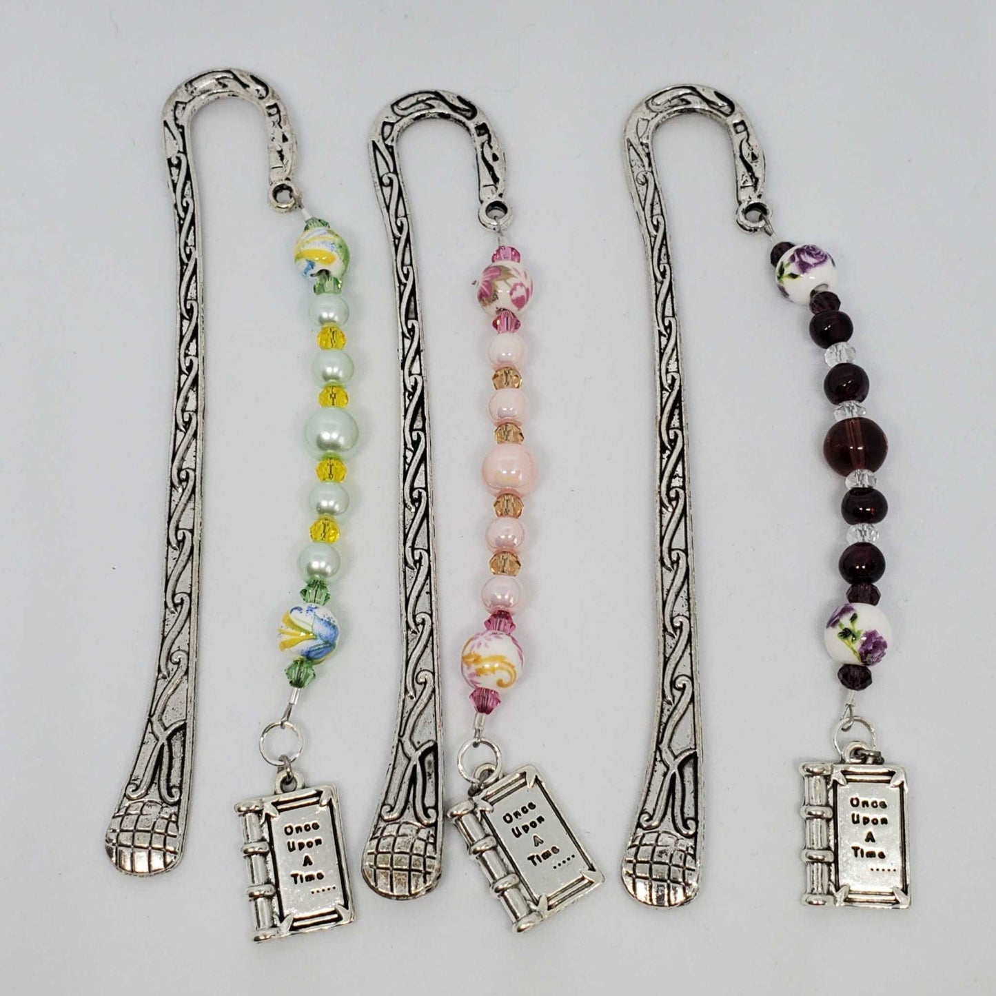 Metal hook bookmarks with floral porcelain beads, crystals, and book-shaped pendants in three color variations
