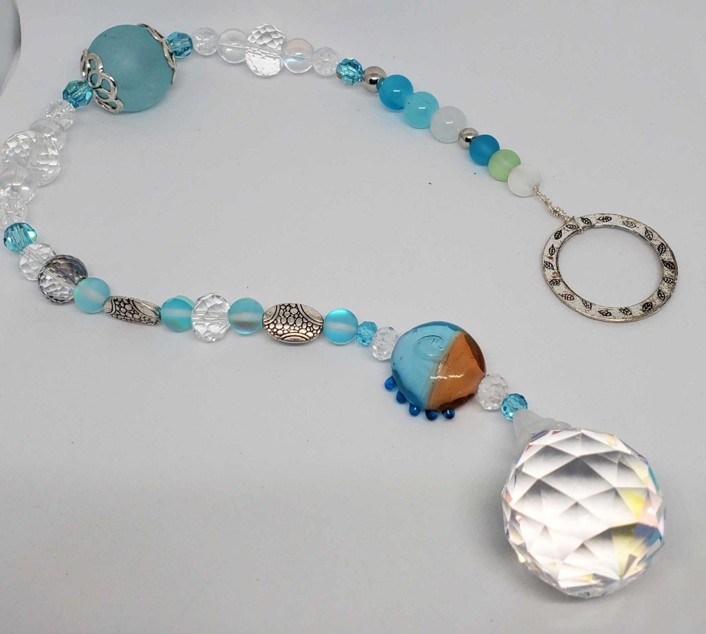 Crystal suncatcher with teardrop crystal and turquoise beads hanging in sunlight
