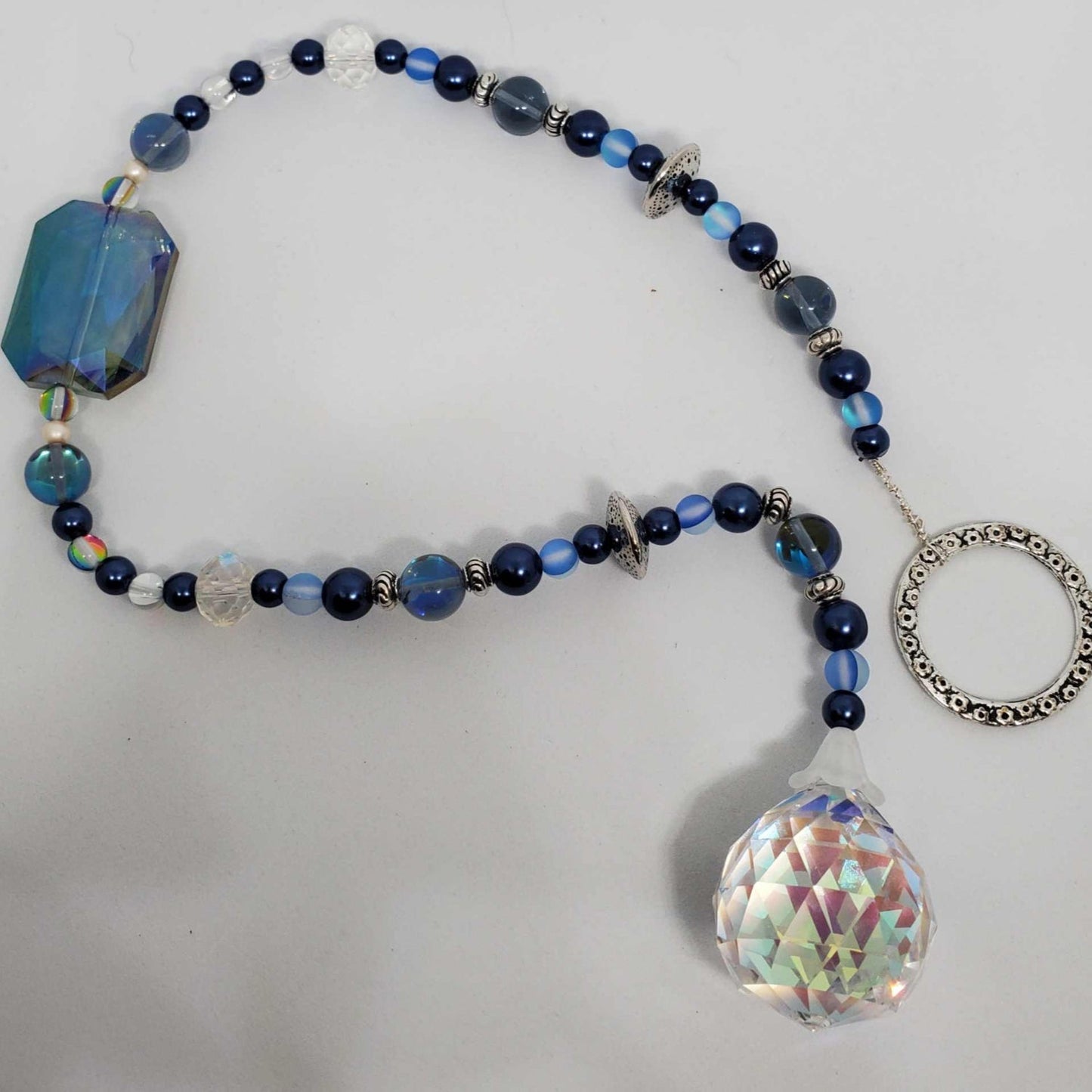 Handcrafted cobalt blue crystal suncatcher with glass and acrylic beads hanging in a sunny window