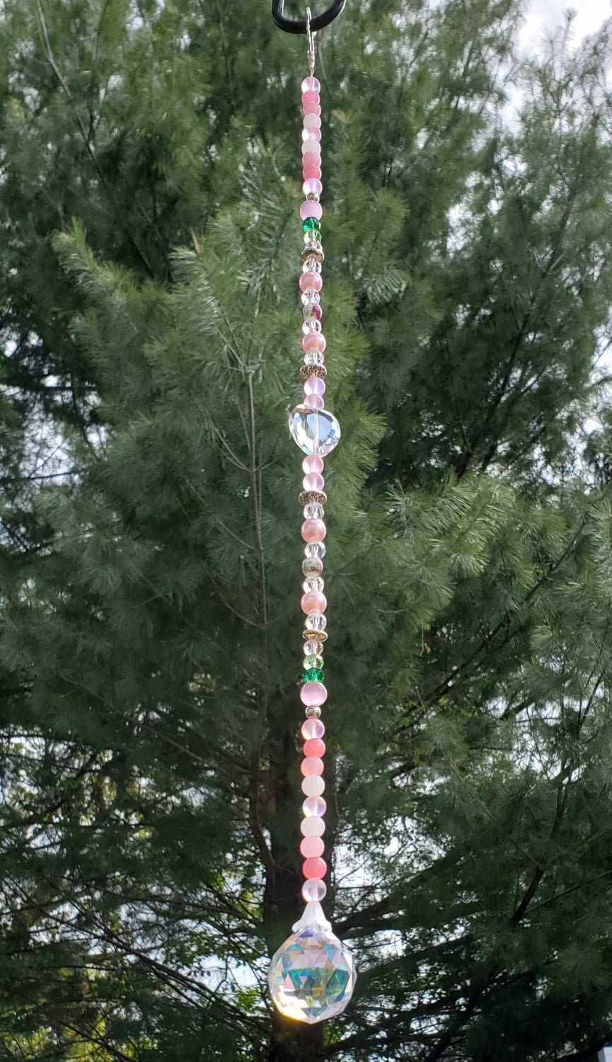 16-inch pink floral crystal suncatcher with teardrop prism, glass beads, porcelain flowers, and pewter accents hanging outdoors