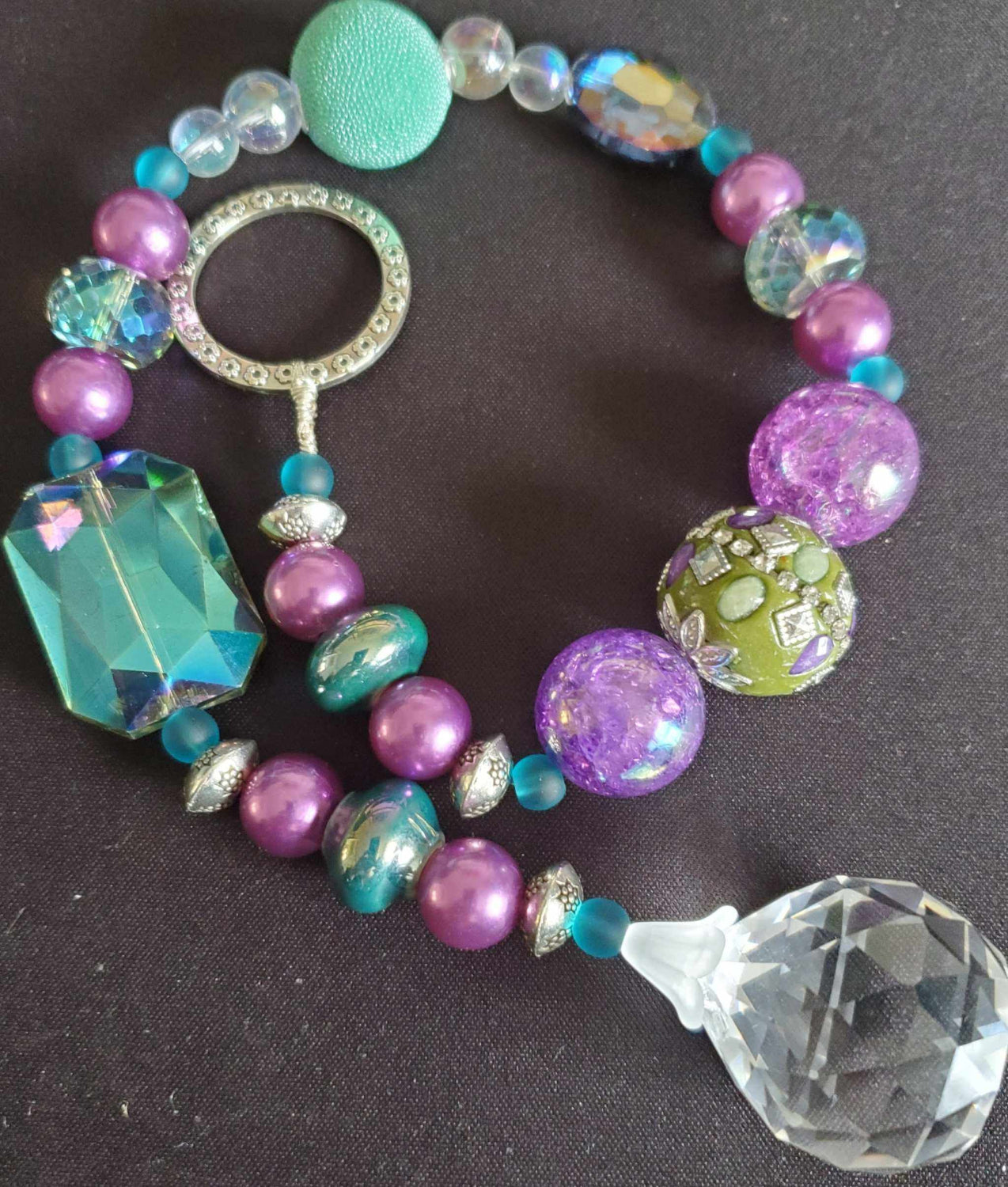 Colorful Crystal Suncatcher with purple, green, and turquoise beads and a clear prism pendant on black background