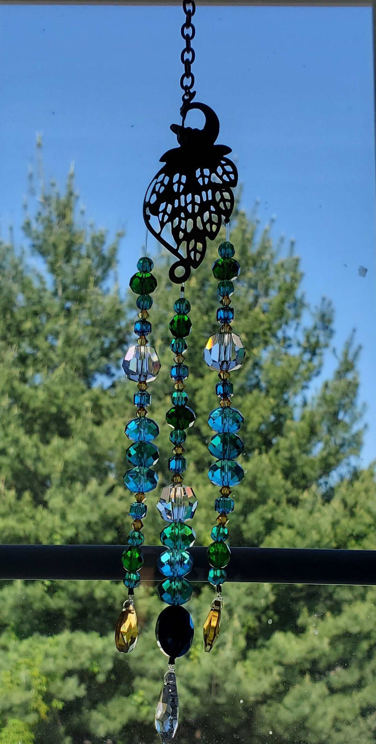 Handcrafted crystal suncatcher with antiqued brass peacock, blue and emerald beads, and topaz prism crystal hanging on copper chain