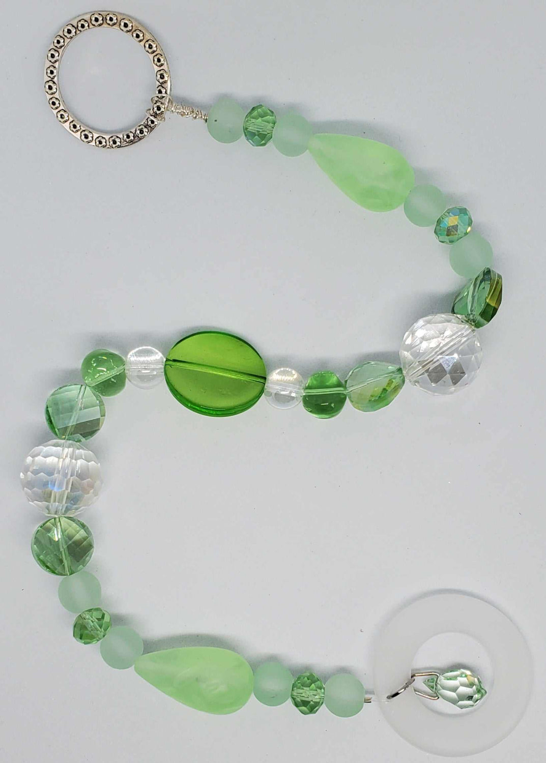 Green and clear crystal suncatcher with vintage-inspired beads and a decorative silver ring for hanging.