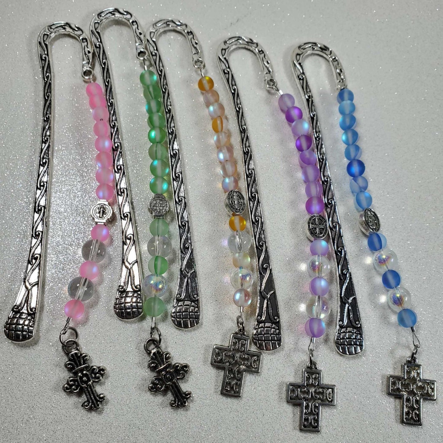 Set of five ornate metal bookmarks with pewter cross charms and colorful glass bead strands in pink, green, yellow, purple, and blue.