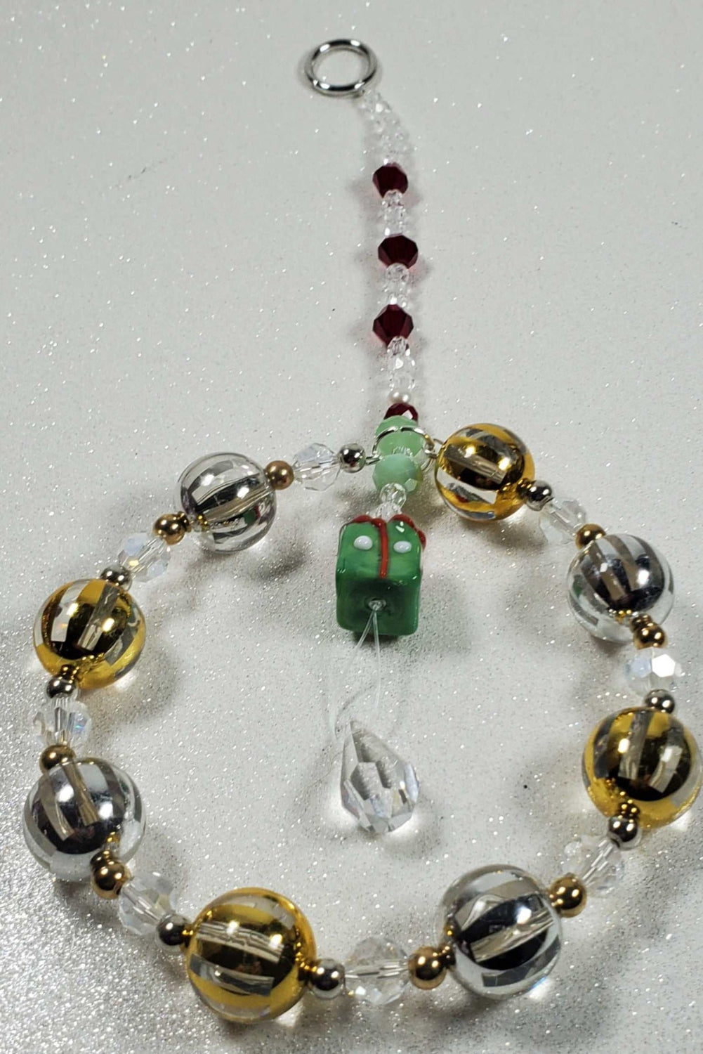 Holiday ornament beaded suncatcher with glass present, acrylic and brass accents, and teardrop prism sparkle