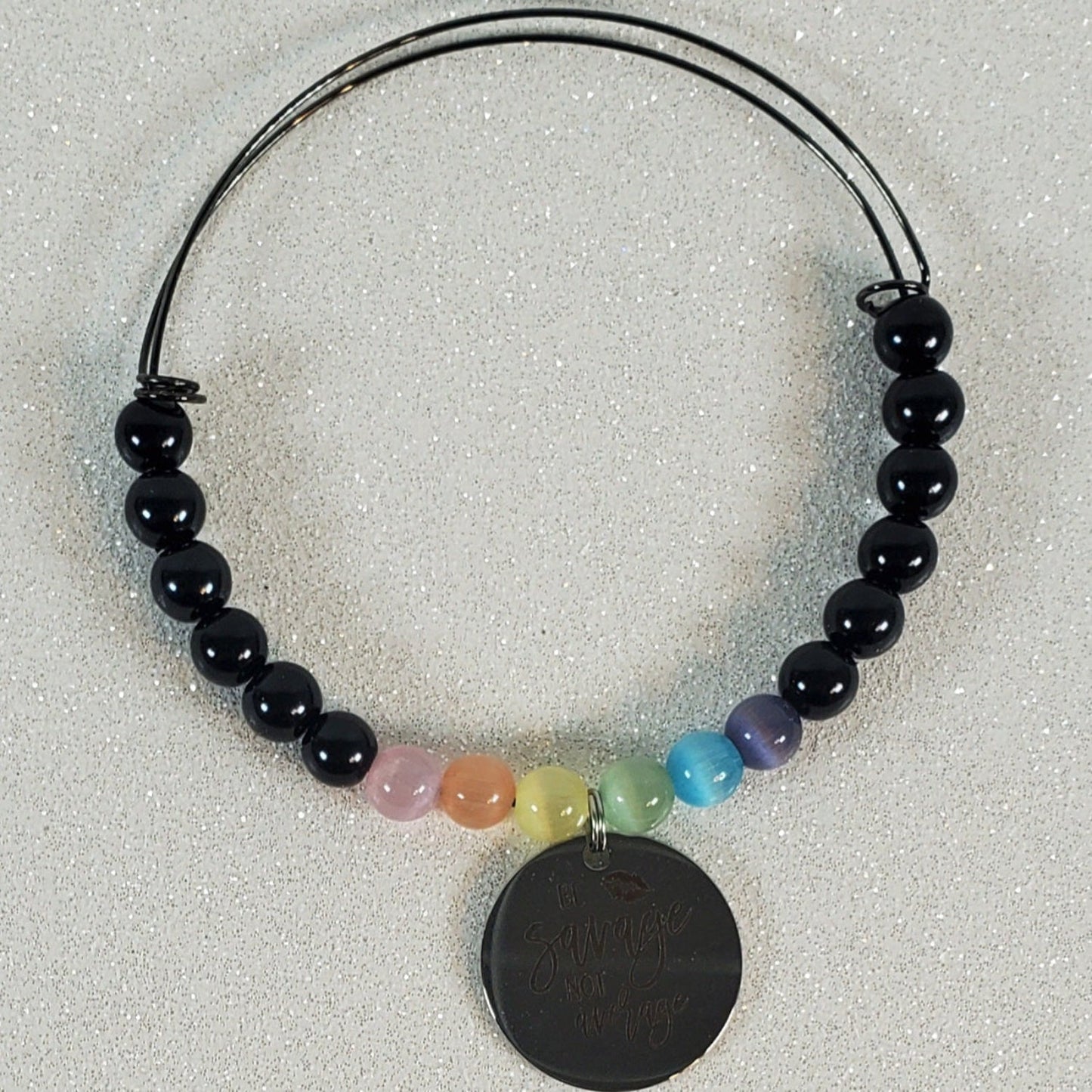 Bracelet with black beads and a round black pendant on a light gray background