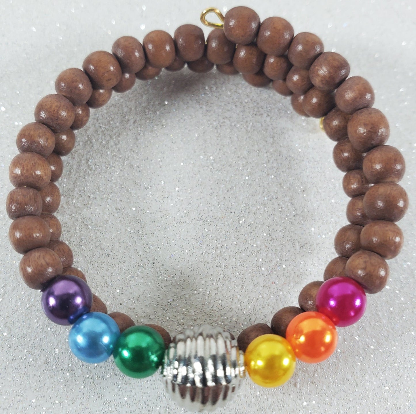 Child's rainbow cuff bracelet with wooden and colorful acrylic pearl beads and a silver pewter centerpiece.