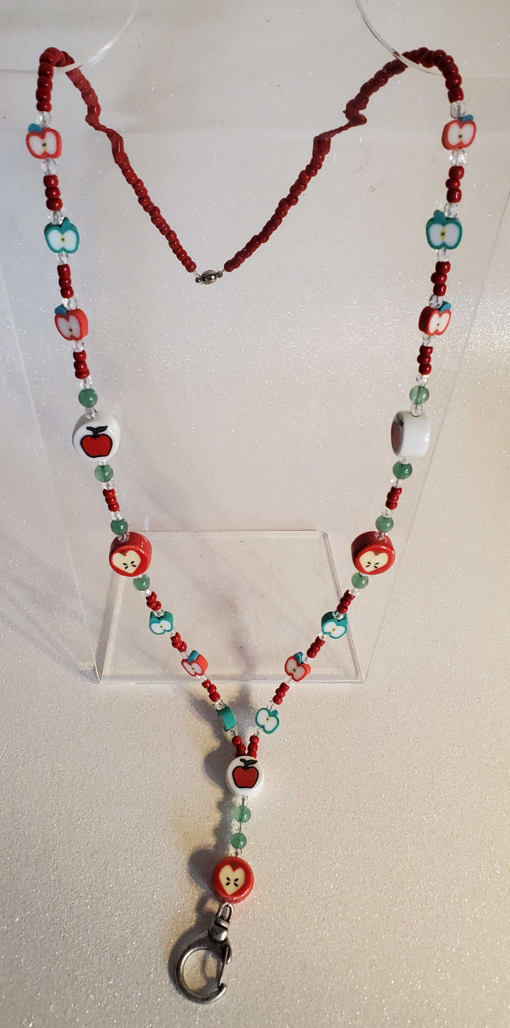 Apple-themed lanyard with red and green beads featuring apple designs and a metal clasp for holding ID or keys.