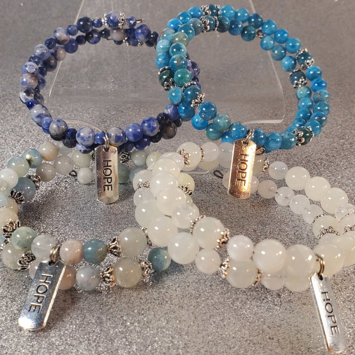 Set of gemstone bracelets with blue, white, and multicolored beads featuring "Hope" engraved pewter charms on adjustable memory wire cuffs.
