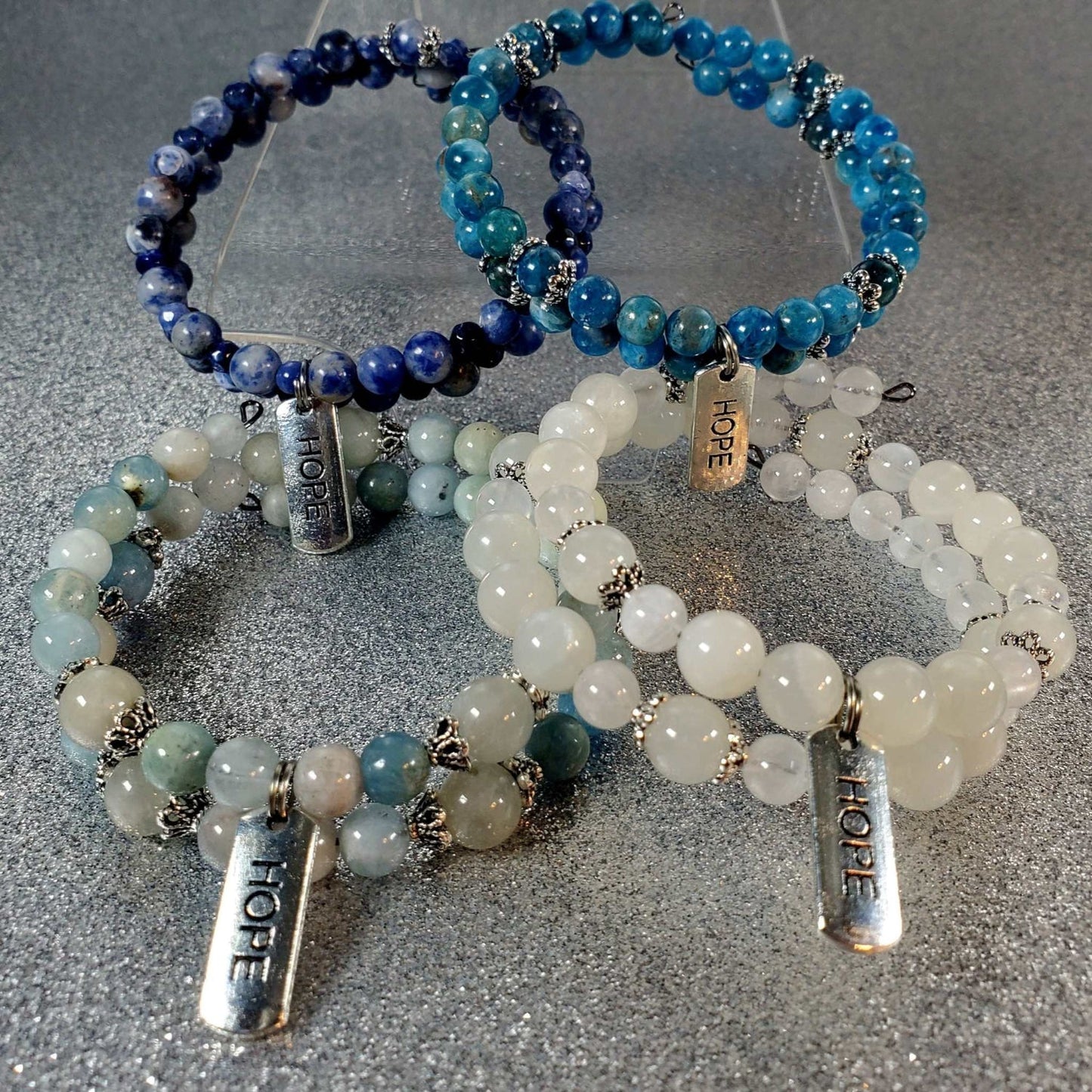 Set of gemstone bracelets with blue, white, and green beads featuring pewter "Hope" charms on adjustable memory wire cuffs.