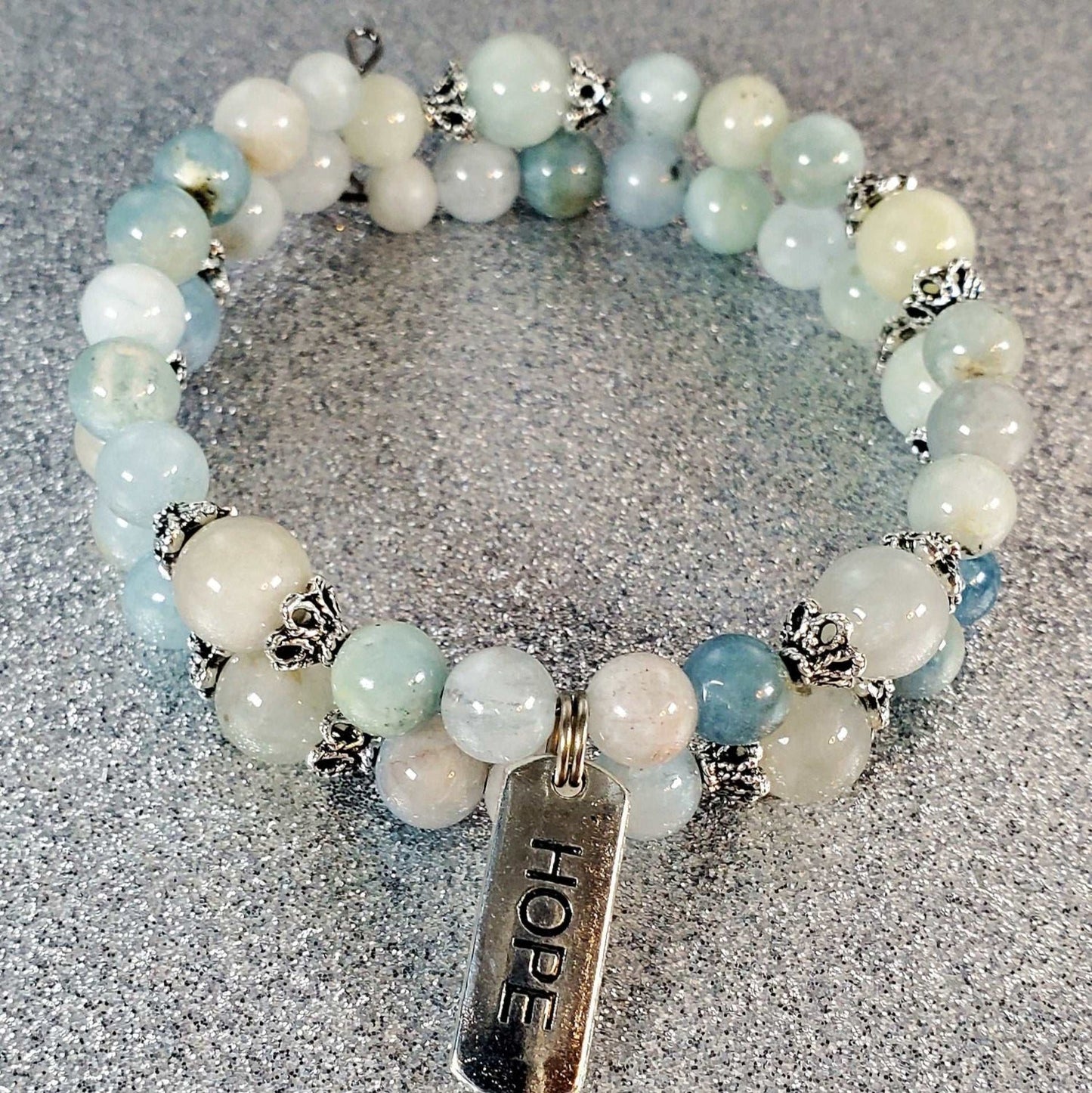 Adjustable gemstone bracelet with blue and white beads and a pewter charm engraved with "Hope"