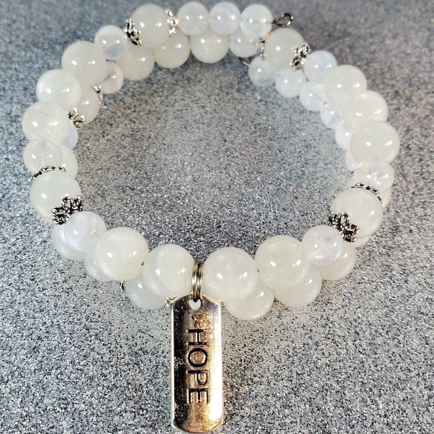 White gemstone bracelet with adjustable memory wire cuff and pewter charm engraved with the word "Hope"