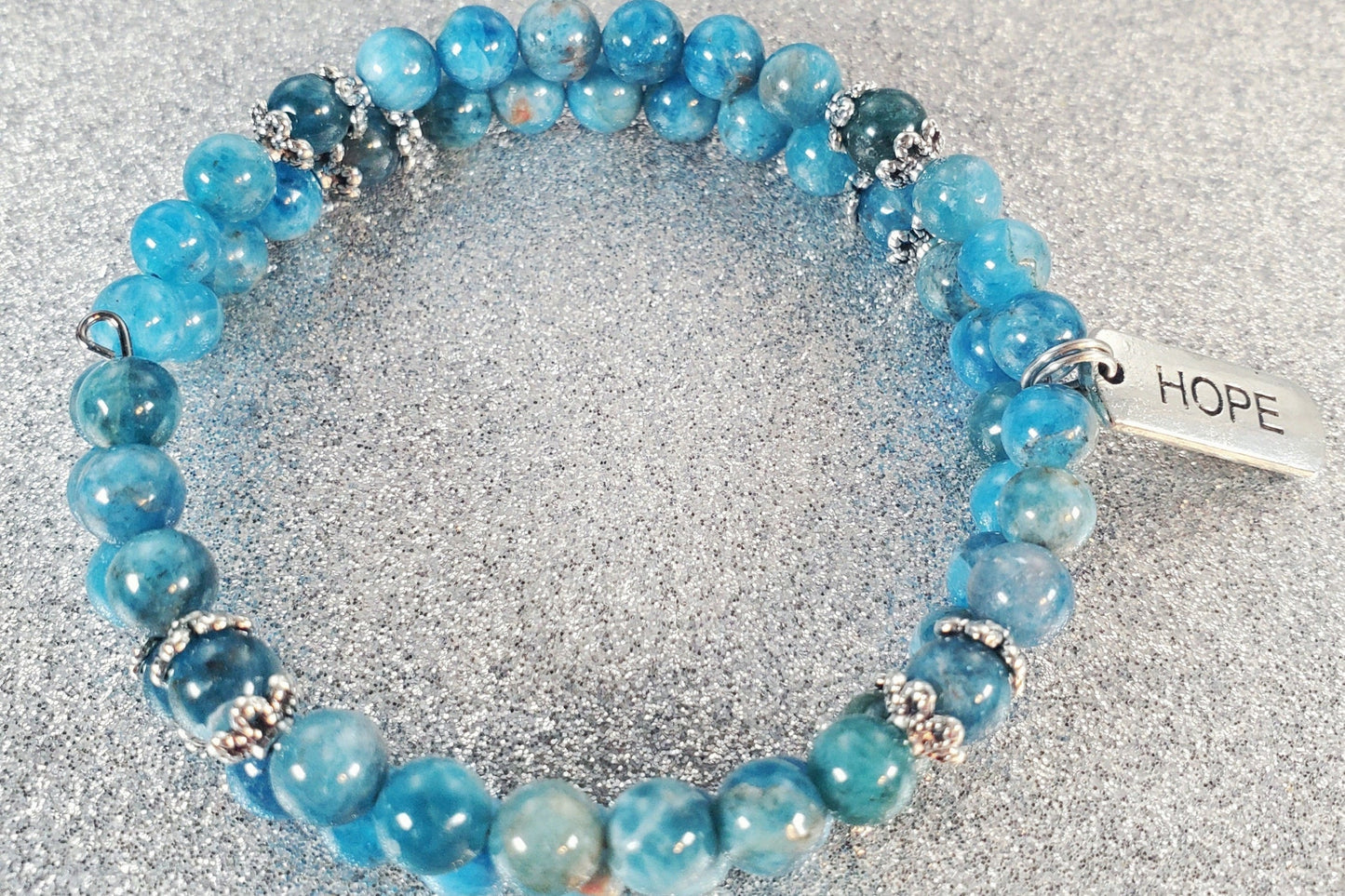 Adjustable blue gemstone bracelet with pewter "Hope" charm, symbolizing inner strength and encouragement.