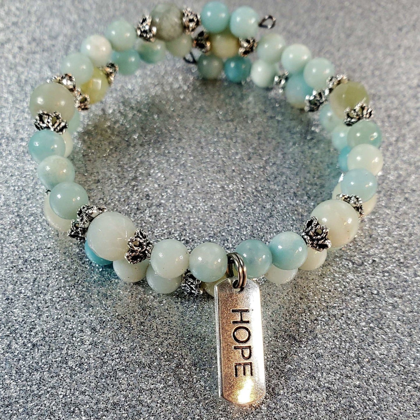 Adjustable gemstone bracelet with blue and white beads and a pewter charm engraved with "Hope"