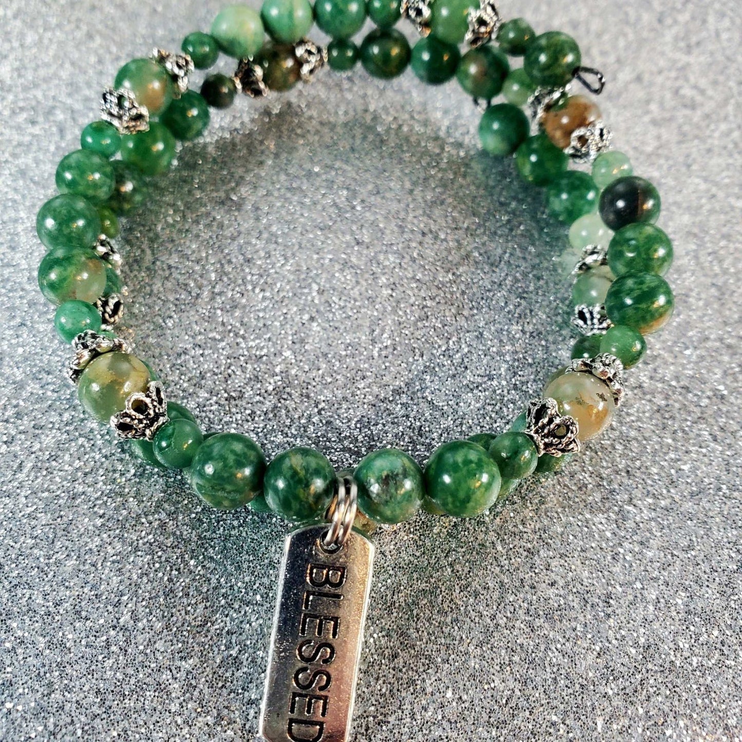 Green gemstone bracelet with silver accents and a pewter "Blessed" charm on a flexible memory wire band