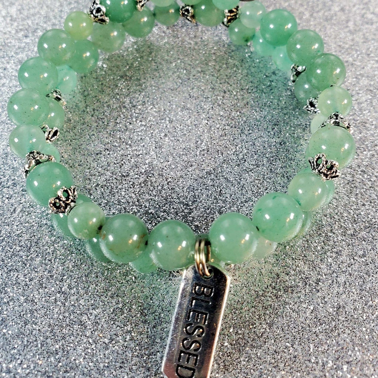 Green gemstone bracelet with silver bead accents and a pewter "Blessed" charm on flexible memory wire