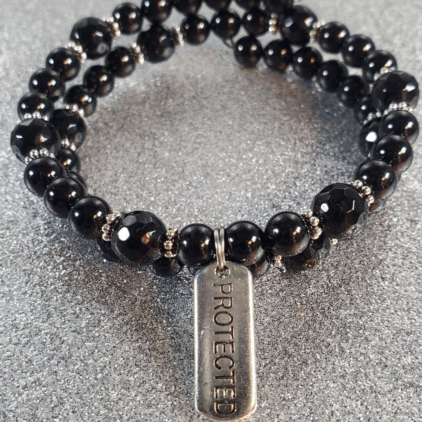 Handcrafted gemstone bracelet with black tourmaline beads and a pewter "Protected" charm on flexible memory wire.