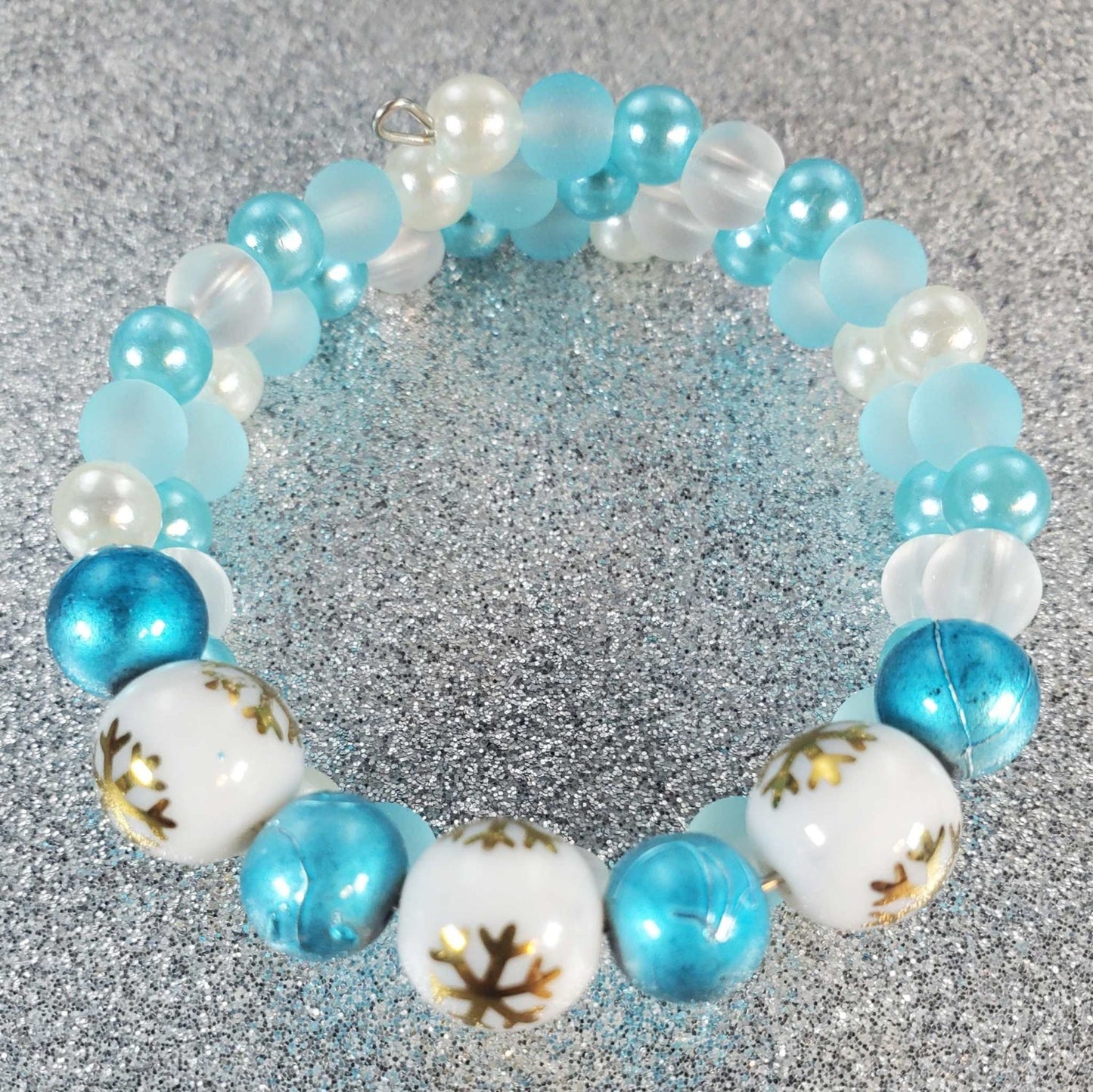 Child's holiday bracelet with blue, white, and pearl beads featuring snowflake designs on memory wire band.