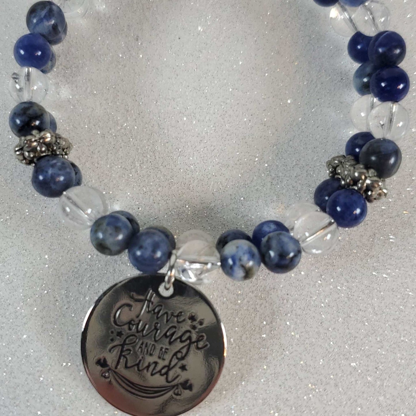 Inspirational gemstone bracelet with blue and clear beads and a "Have Courage Be Kind" engraved charm cuff