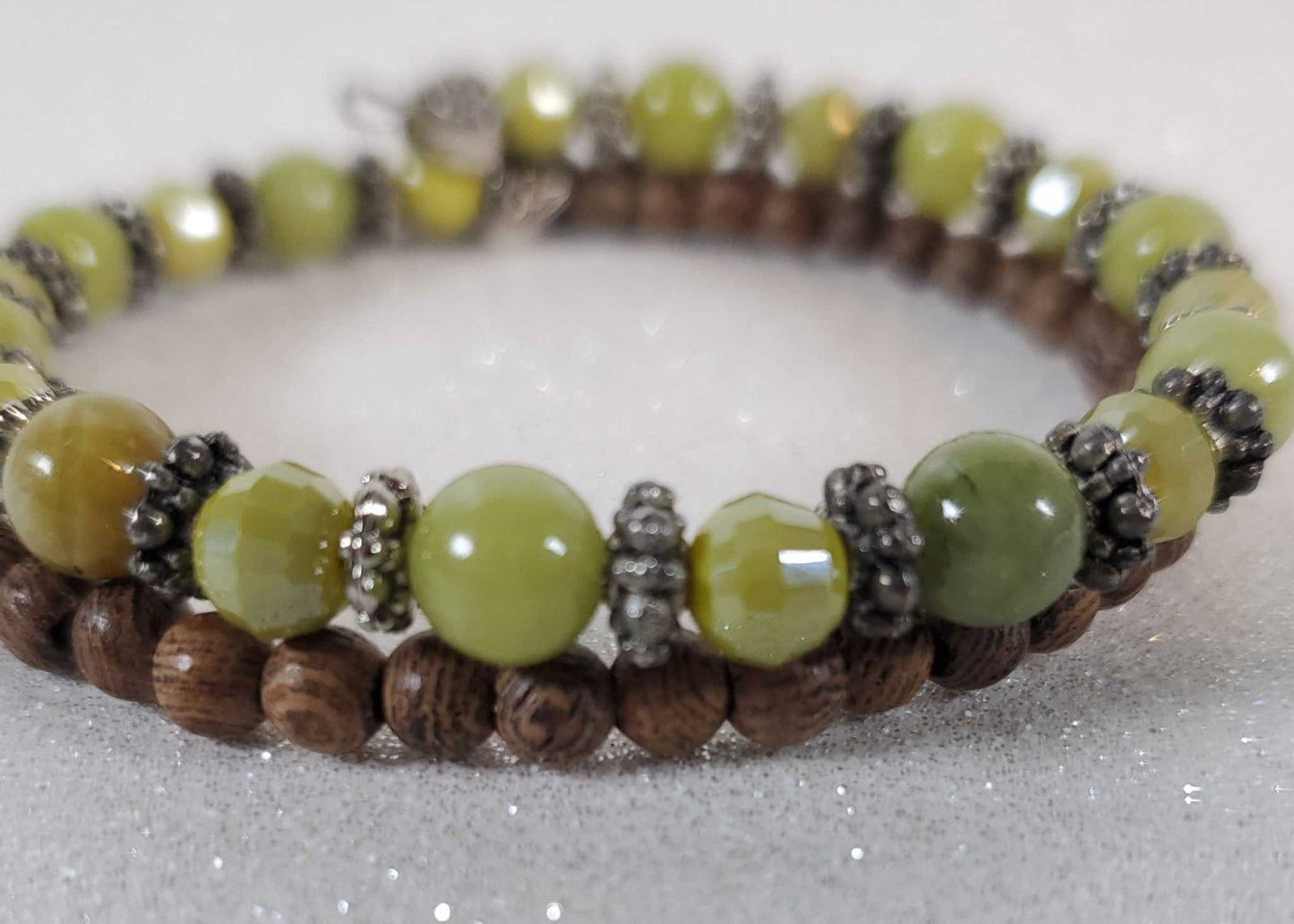 Handcrafted gemstone bracelet with faceted Peridot beads, coconut wood, and pewter accents on flexible memory wire wrap design