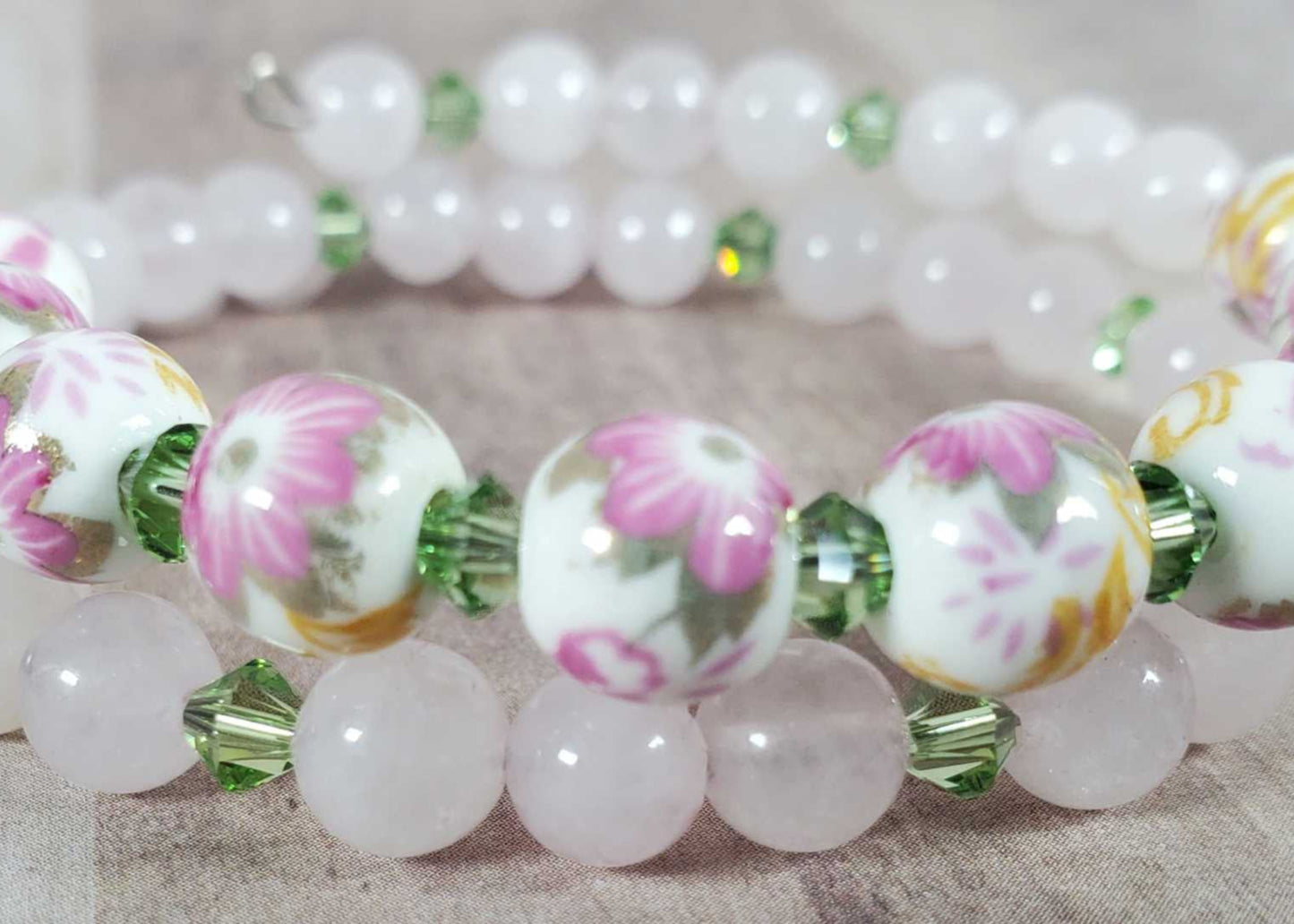 Floral bracelet with porcelain floral beads and green gemstone accents on a flexible memory wire band