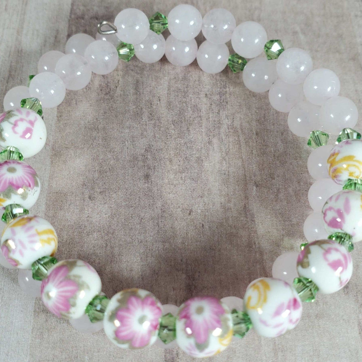 Floral bracelet featuring 8mm porcelain floral beads and green gemstone accents on flexible memory wire.