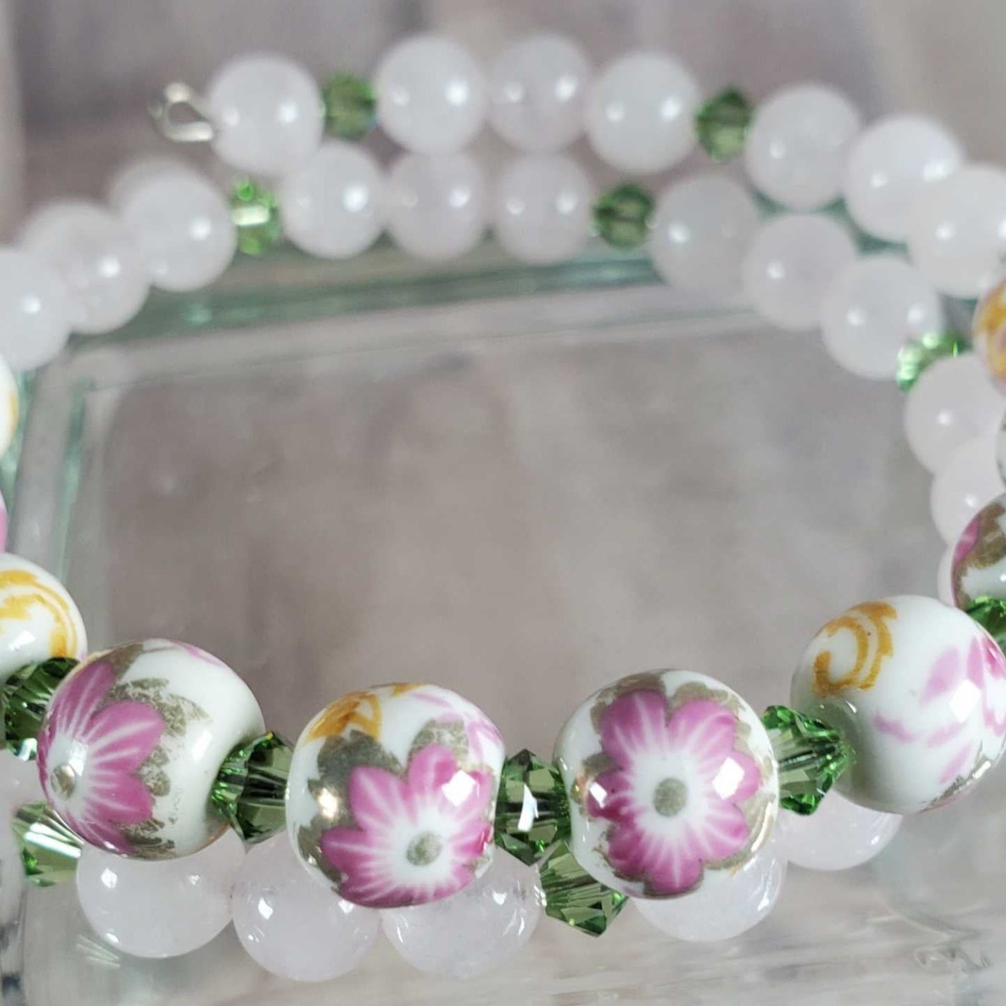 Floral bracelet with porcelain flower beads and green gemstone accents on flexible memory wire
