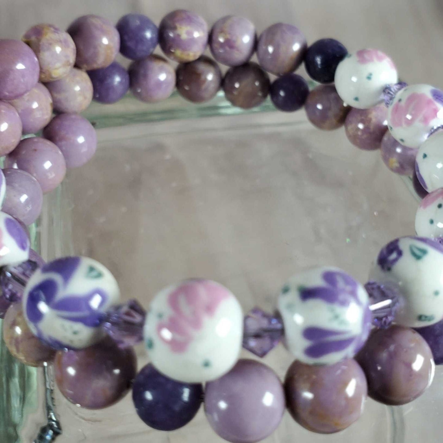 Purple gemstone and white porcelain floral beads bracelet on memory wire.