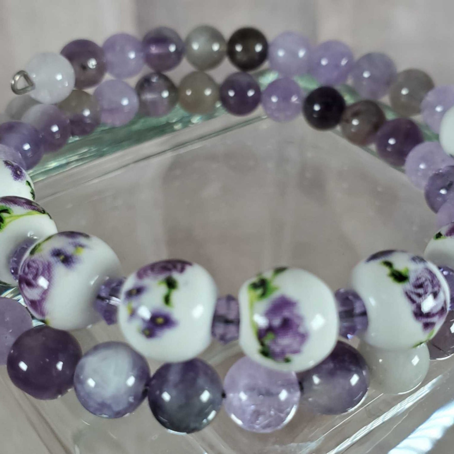 Floral bracelet with purple gemstone beads and white porcelain floral beads on memory wire.