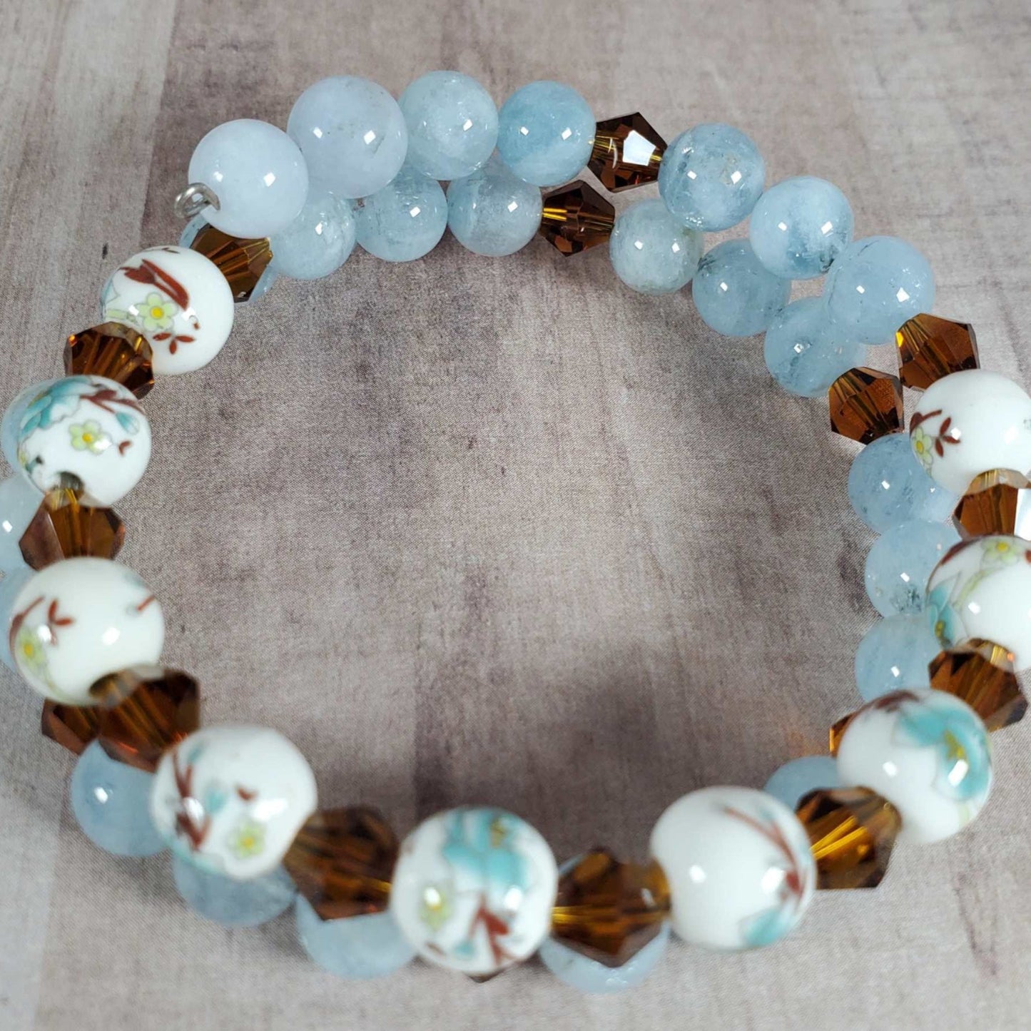 Floral bracelet with blue aquamarine, brown gemstones, and white porcelain floral beads on flexible memory wire
