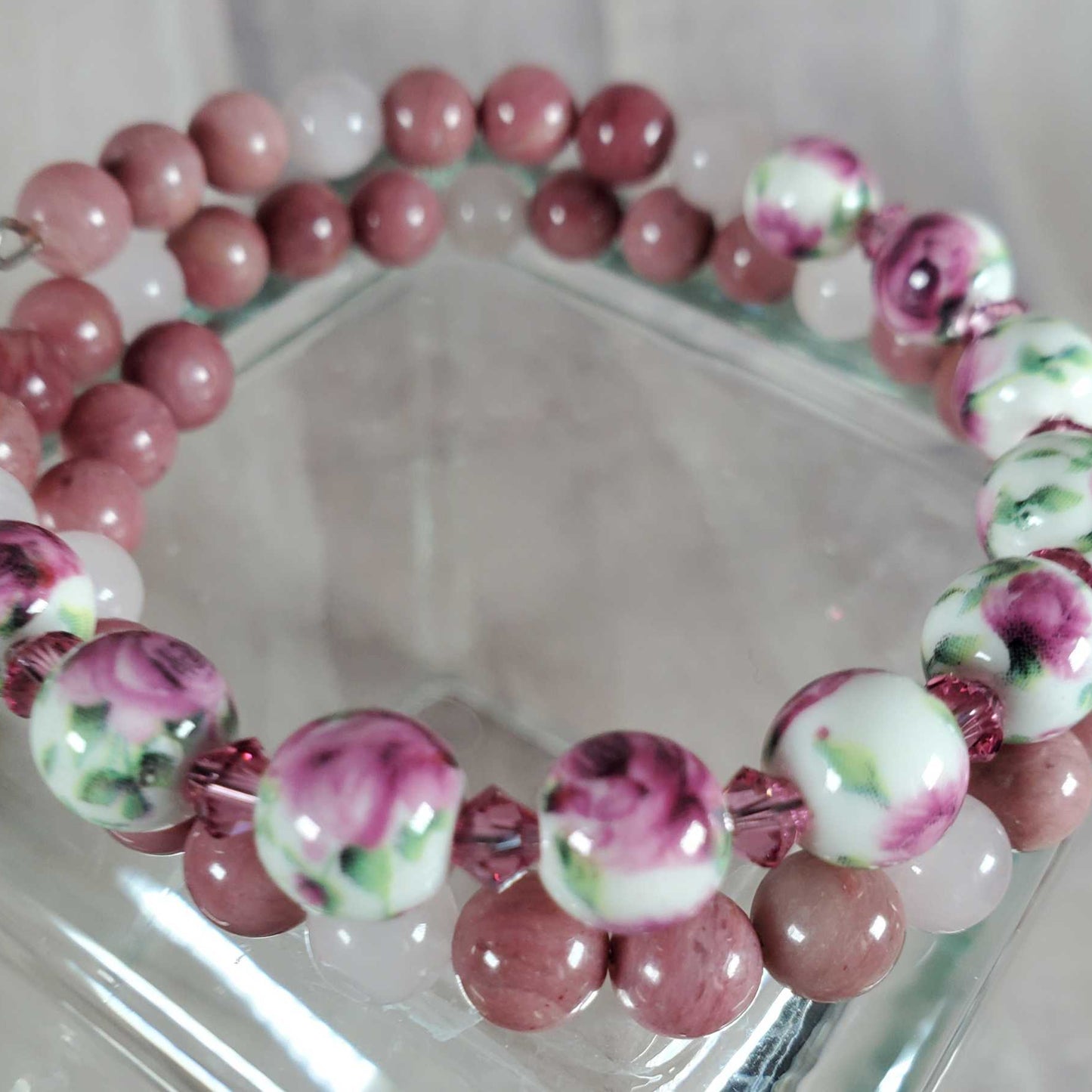 Floral bracelet with gemstone and porcelain floral beads in pink, white, and green tones on flexible memory wire.