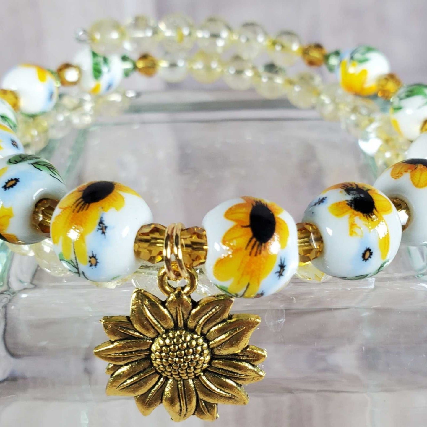 Floral bracelet featuring 8mm porcelain sunflower beads, citrine gemstones, Austrian crystals, and a detailed brass sunflower charm on adjustable memory wire.