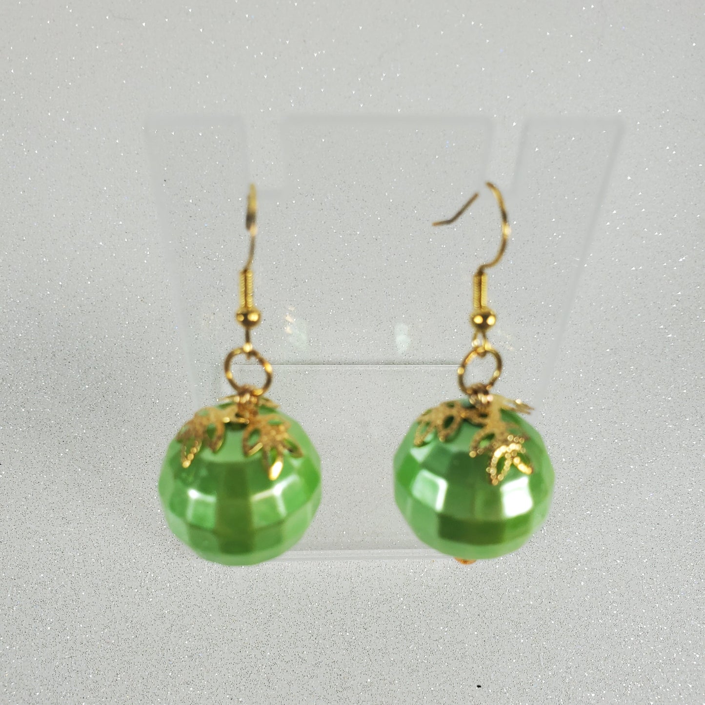 Green acrylic earrings with gold hooks on a light gray background