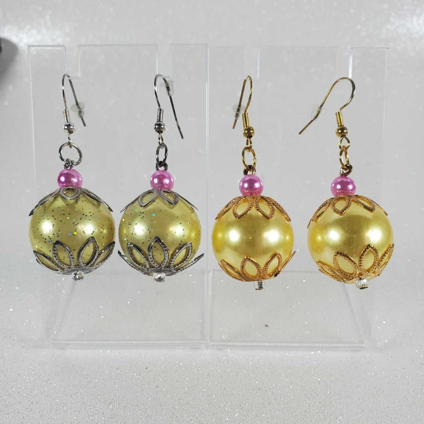 Pair of gold and yellow beaded earrings with pink beads on a clear background