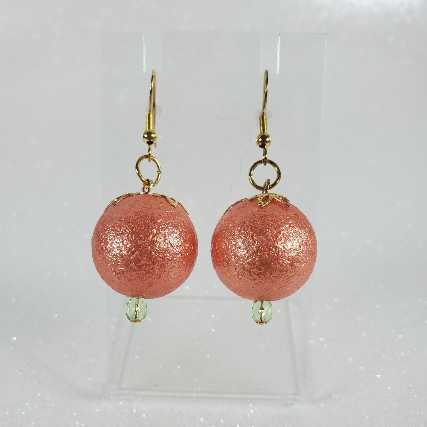 Orange round earrings with gold hooks on a clear background