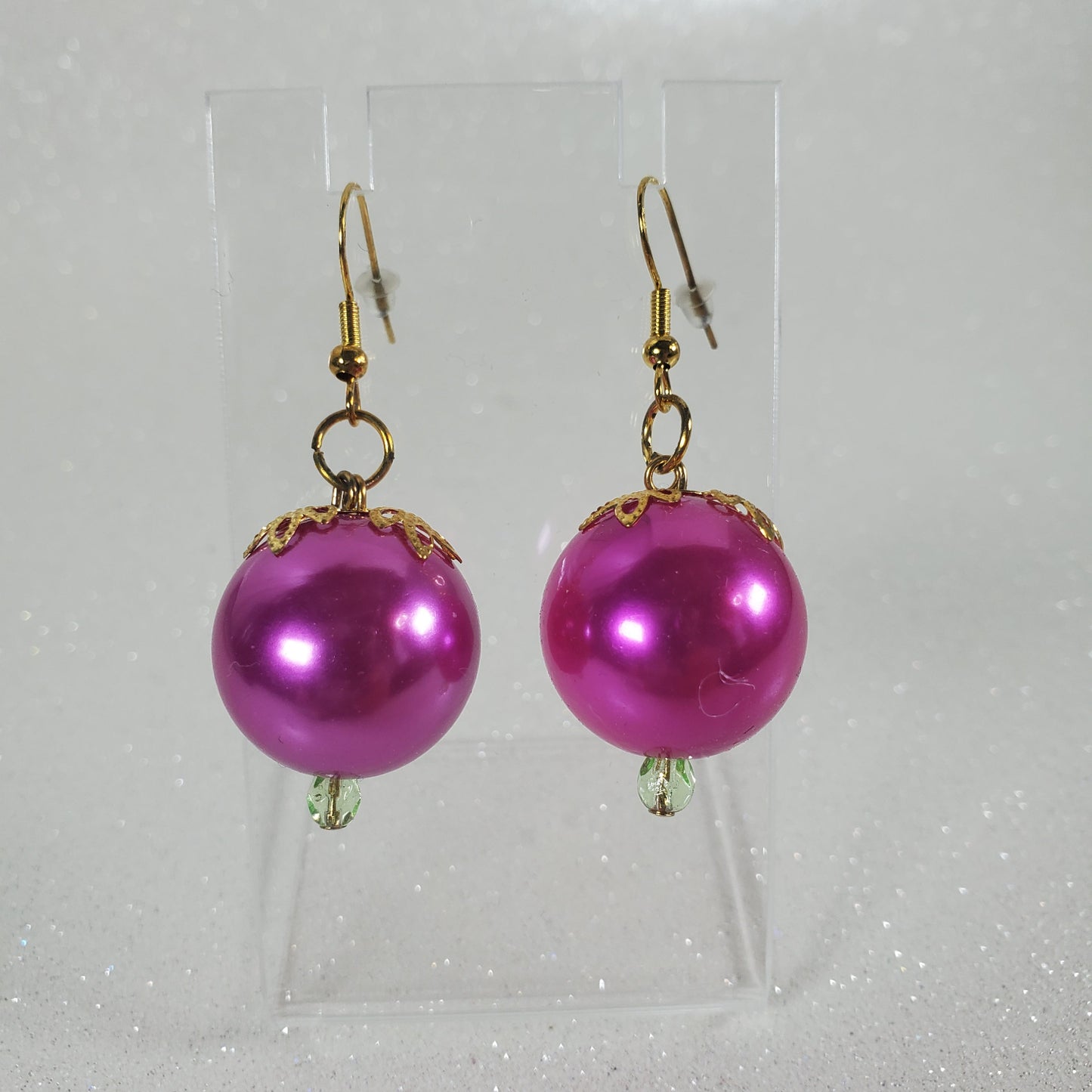 Pink pearl earrings with gold hooks on a white background