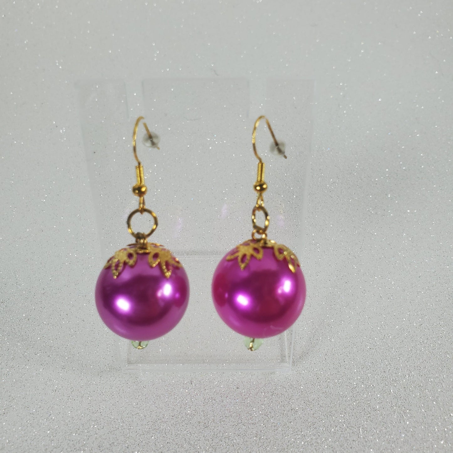 Fushia earrings with gold accents on a gray background