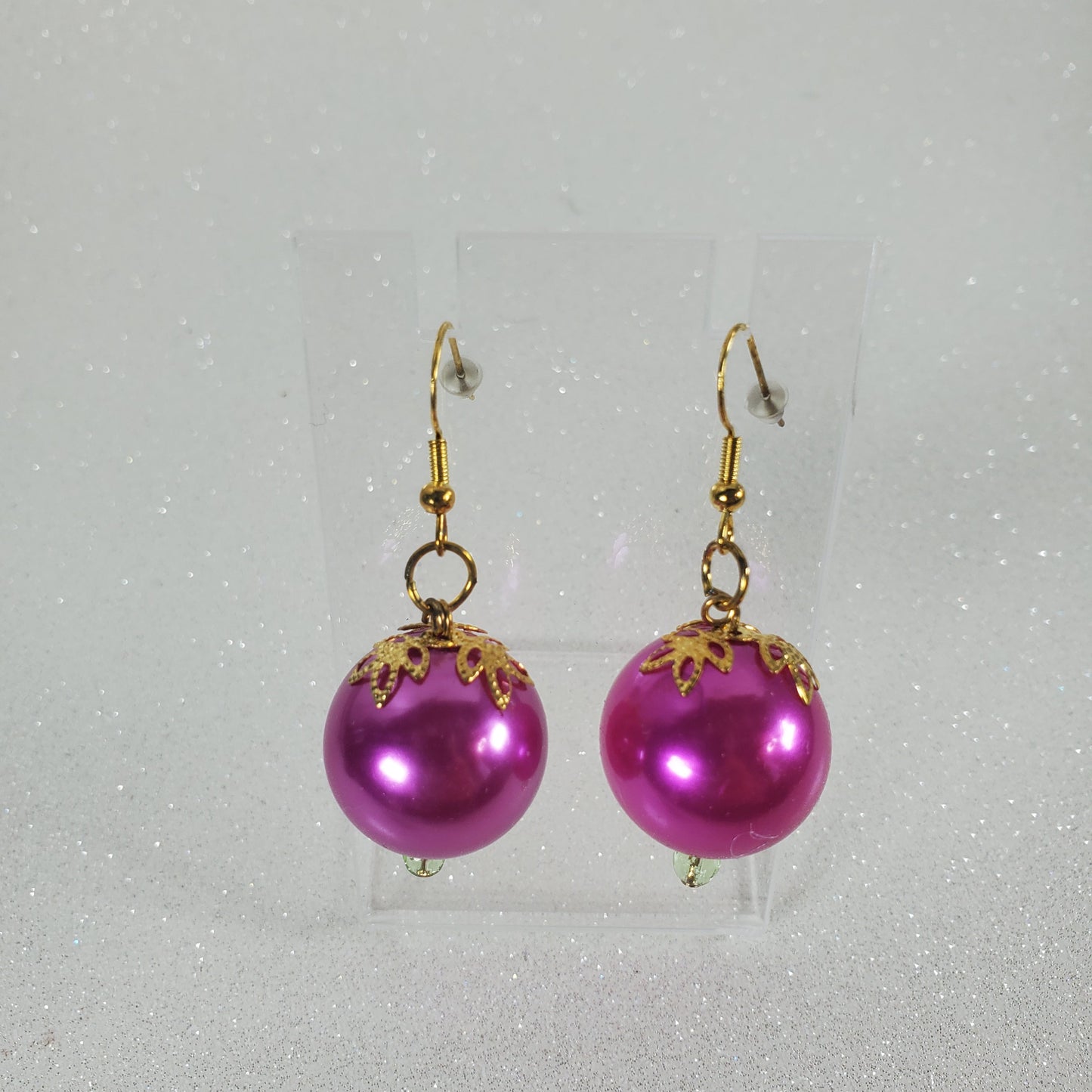 Fushia pearl earrings with gold hooks on a light gray background
