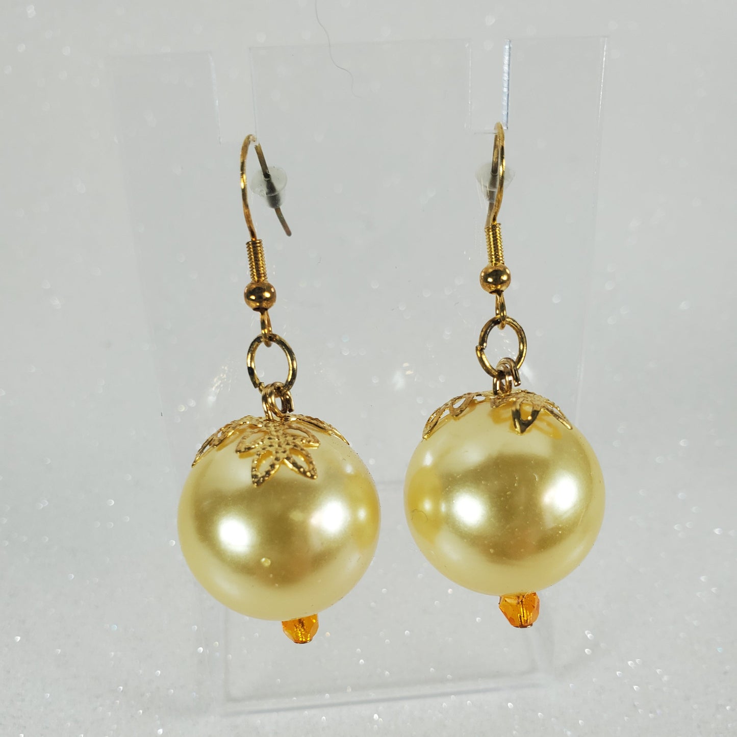 Gold pearl earrings on a light gray background