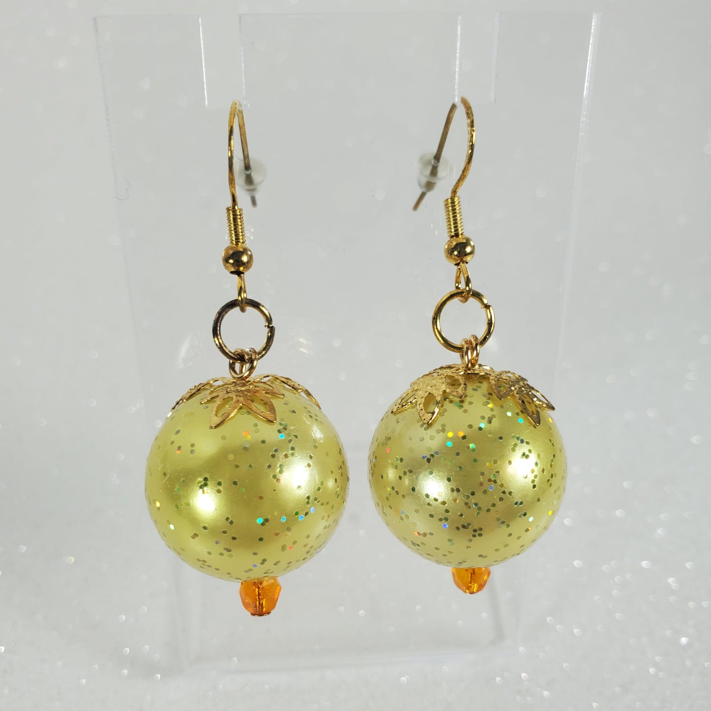 Gold glittery sphere earrings on a light gray background