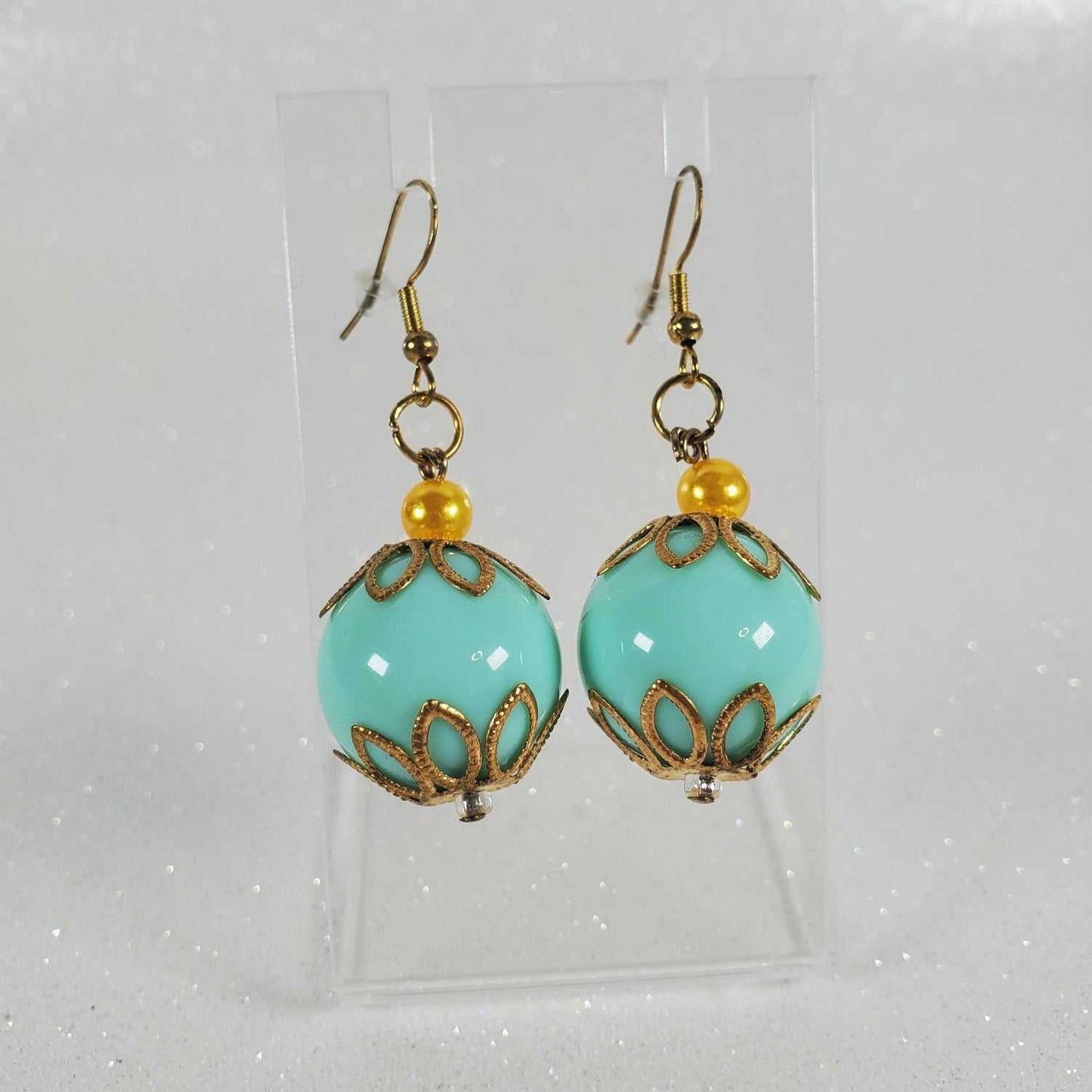 Turquoise earrings with gold accents and yellow beads on a clear background