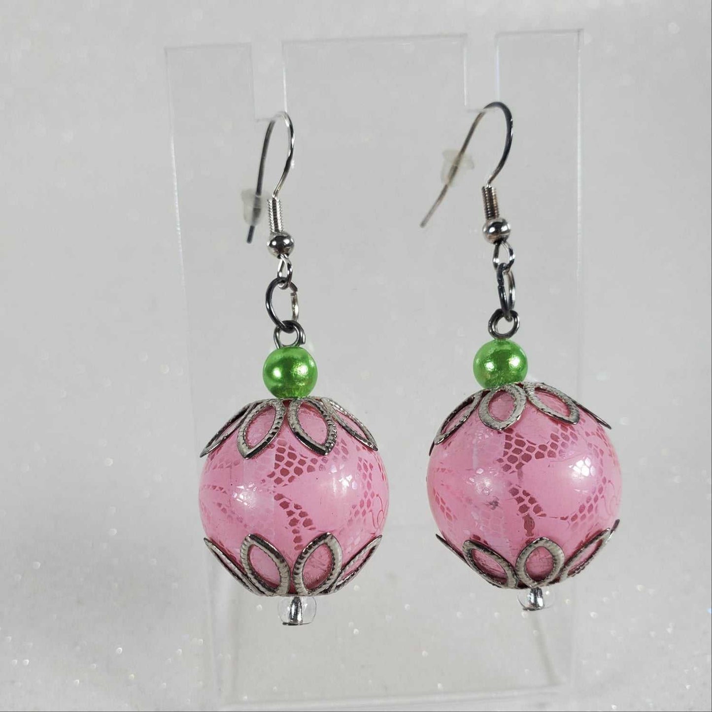 Pink beaded earrings with green accents on a white background