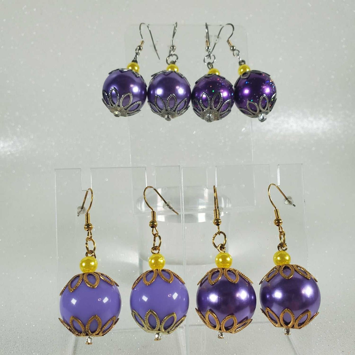 Set of purple beaded earrings with gold accents on a clear background