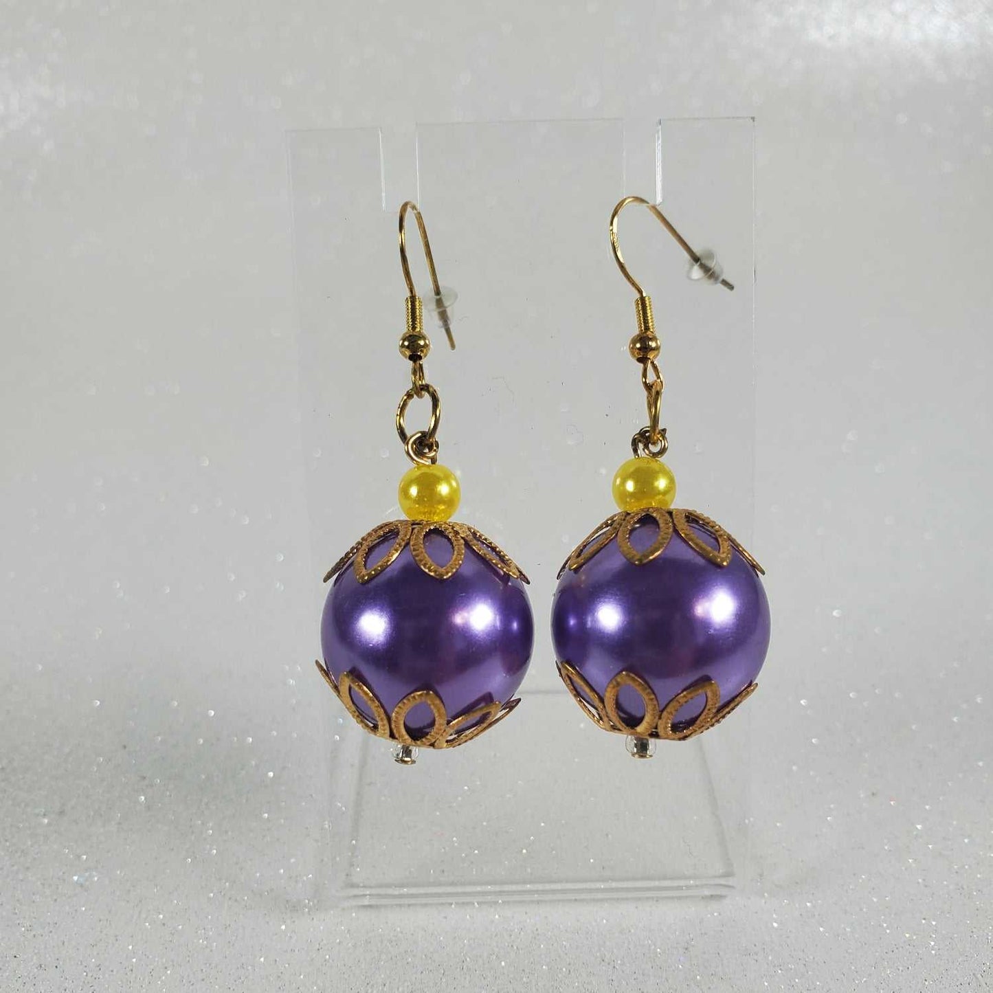 Purple earrings with gold accents on a white background