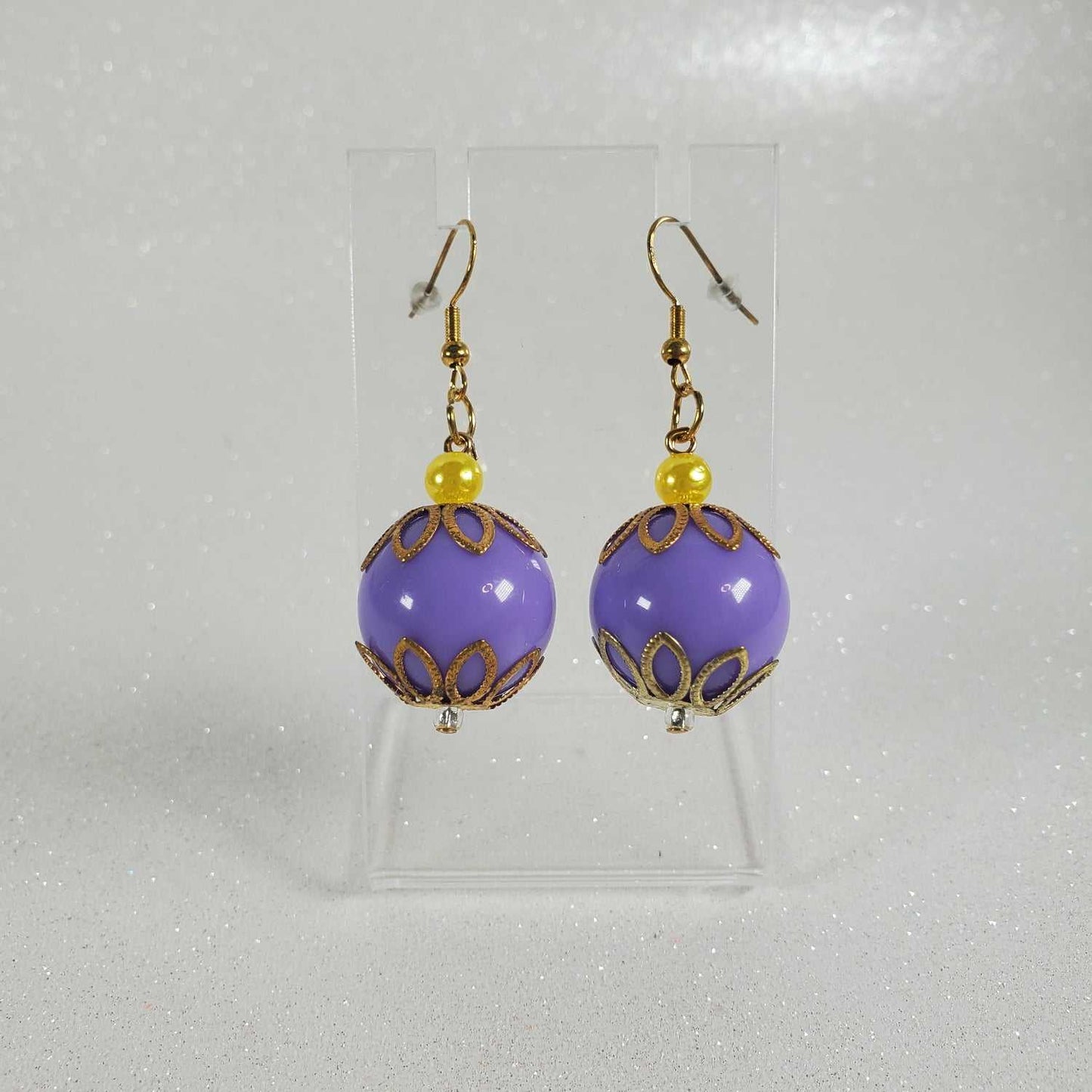 Purple round earrings with gold accents on a gray background